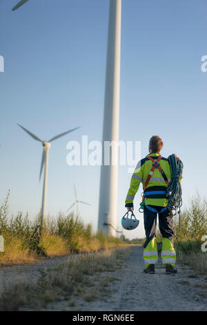 Sur le chemin du technicien sur le terrain à une ferme éolienne avec matériel d'escalade Banque D'Images