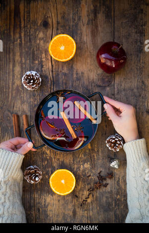 Woman's hands holding marmite de vin chaud avec des tranches d'orange et épices Banque D'Images
