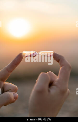 Close-up of man's hand holding un sablier au coucher du soleil Banque D'Images