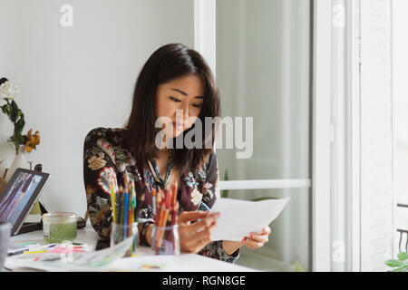 Illustrator contenu assis à un bureau dans l'atelier à dessin à Banque D'Images