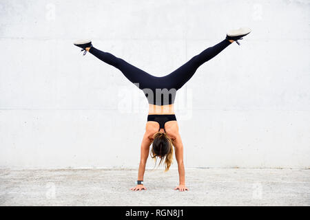 Athlète doing handstand in front of white wall Banque D'Images