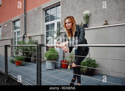 Certain jeune femme portant veste biker leaning on railing balcon