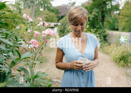 Femme debout dans jardin avec tasse de café Banque D'Images
