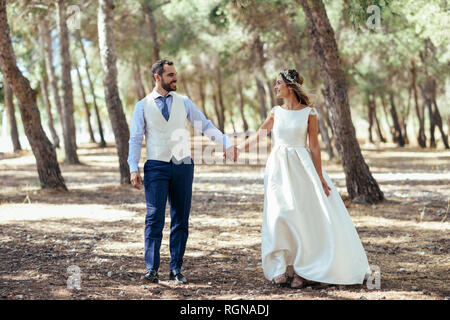 Happy young couple marche main dans la main dans la forêt de pins Banque D'Images