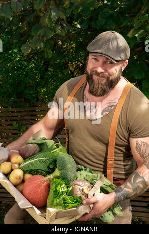 L'homme mature avec caisse de transport des légumes dans son jardin Banque D'Images