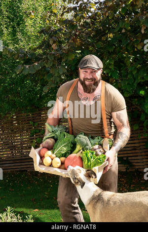 L'homme mature avec caisse de transport des légumes dans son jardin Banque D'Images