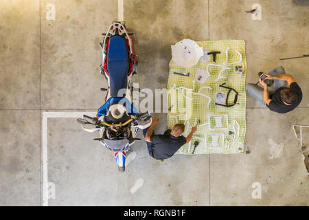 Deux hommes en plaçant les tâches à côté de l'atelier en moto Banque D'Images