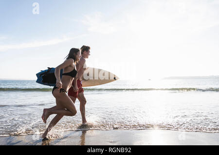 France, Bretagne, young couple with surfboard tournant dans la mer Banque D'Images