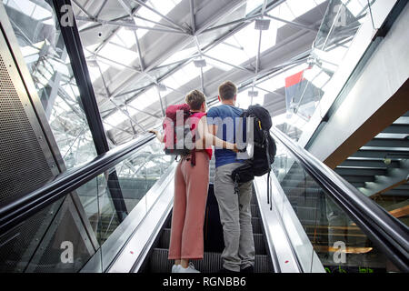 Vue arrière du couple sur l'escalator à l'aéroport. Banque D'Images