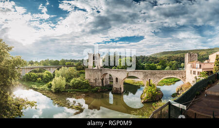 Besalu, Gérone, Catalogne, Espagne. Célèbre Roman médiéval vieux de Besalu Pont au-dessus de la rivière Fluvia nuageux dans la journée d'été. Vue panoramique Banque D'Images