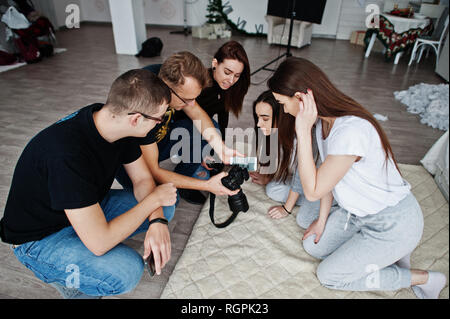 L'équipe de photographes montrant des images à l'écran de l'appareil photo pour des jumeaux modèles filles sur studio. Photographe professionnel sur le travail. Banque D'Images