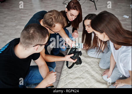 L'équipe de photographes montrant des images à l'écran de l'appareil photo pour des jumeaux modèles filles sur studio. Photographe professionnel sur le travail. Banque D'Images