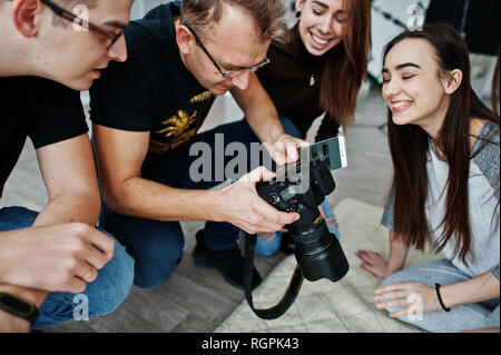 L'équipe de photographes montrant des images à l'écran de l'appareil photo pour des jumeaux modèles filles sur studio. Photographe professionnel sur le travail. Banque D'Images