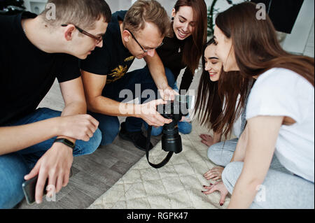 L'équipe de photographes montrant des images à l'écran de l'appareil photo pour des jumeaux modèles filles sur studio. Photographe professionnel sur le travail. Banque D'Images