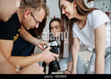 L'équipe de photographes montrant des images à l'écran de l'appareil photo pour des jumeaux modèles filles sur studio. Photographe professionnel sur le travail. Banque D'Images