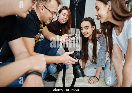 L'équipe de photographes montrant des images à l'écran de l'appareil photo pour des jumeaux modèles filles sur studio. Photographe professionnel sur le travail. Banque D'Images