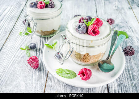 Des idées de recettes pour l'été petit-déjeuner diététique, sain matin dessert Cheesecake dans des bocaux avec des baies d'été portionné - framboise, bleuet, blackberry. O Banque D'Images