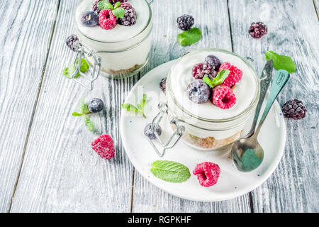 Des idées de recettes pour l'été petit-déjeuner diététique, sain matin dessert Cheesecake dans des bocaux avec des baies d'été portionné - framboise, bleuet, blackberry. O Banque D'Images