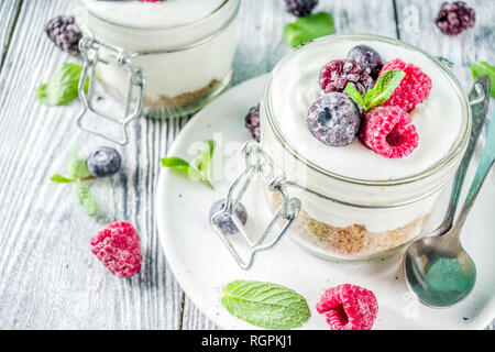 Des idées de recettes pour l'été petit-déjeuner diététique, sain matin dessert Cheesecake dans des bocaux avec des baies d'été portionné - framboise, bleuet, blackberry. O Banque D'Images