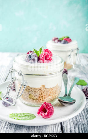 Des idées de recettes pour l'été petit-déjeuner diététique, sain matin dessert Cheesecake dans des bocaux avec des baies d'été portionné - framboise, bleuet, blackberry. O Banque D'Images