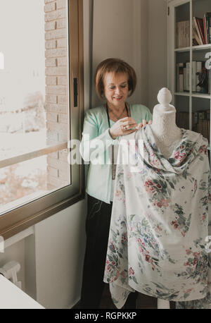 Réglage de la belle femme hauts vêtements ornementaux sur mannequin tout en travaillant en atelier confortable Banque D'Images