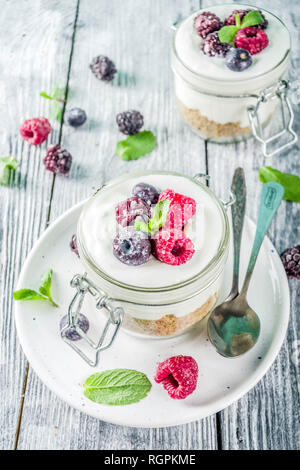 Des idées de recettes pour l'été petit-déjeuner diététique, sain matin dessert Cheesecake dans des bocaux avec des baies d'été portionné - framboise, bleuet, blackberry. O Banque D'Images