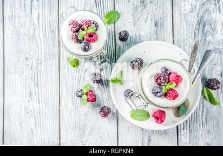 Des idées de recettes pour l'été petit-déjeuner diététique, sain matin dessert Cheesecake dans des bocaux avec des baies d'été portionné - framboise, bleuet, blackberry. O Banque D'Images