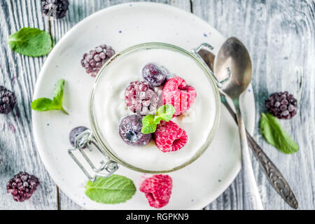 Des idées de recettes pour l'été petit-déjeuner diététique, sain matin dessert Cheesecake dans des bocaux avec des baies d'été portionné - framboise, bleuet, blackberry. O Banque D'Images