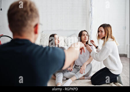 Artiste de préparer deux jumeaux modèles avec ordinateur portable en studio avant séance photo. Show photographe doigt ce qu'il faut faire. Banque D'Images