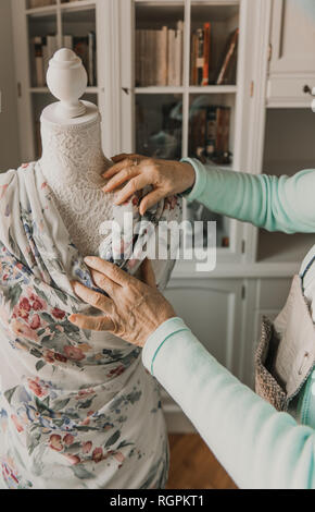 Méconnaissable senior female adapter beau vêtement d'ornement sur mannequin tout en travaillant en atelier confortable Banque D'Images