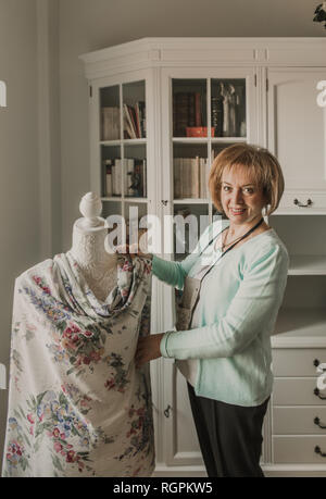 Réglage de la belle femme hauts vêtements ornementaux sur mannequin tout en travaillant en atelier confortable Banque D'Images