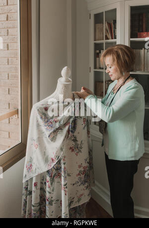 Réglage de la belle femme hauts vêtements ornementaux sur mannequin tout en travaillant en atelier confortable Banque D'Images