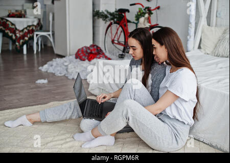 Deux jumeaux modèles avec ordinateur portable en studio à la recherche de quelque chose. Banque D'Images