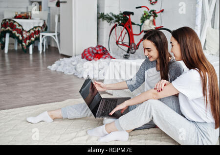 Deux jumeaux modèles avec ordinateur portable en studio à la recherche de quelque chose. Banque D'Images