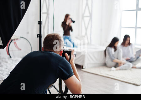 L'équipe de tournage des jumeaux, deux photographes modèles filles sur studio qui sont à la recherche à l'ordinateur portable. Photographe professionnel sur le travail. Banque D'Images