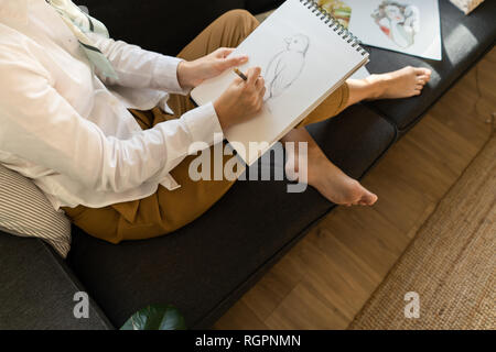 Femme écrit sur papier sur le canapé dans la chambre Banque D'Images