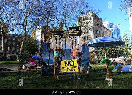 Deux modèles se tiennent sur un 'Beach' de barbelés à l'extérieur des bureaux de TripAdvisor à Soho Square, centre de Londres, dans le cadre d'une campagne d'Amnesty International demande à l'entreprise et d'autres compagnies de voyage pour arrêter l'inscription chambres et activités dans les colonies de peuplement israéliennes dans les territoires palestiniens. Banque D'Images