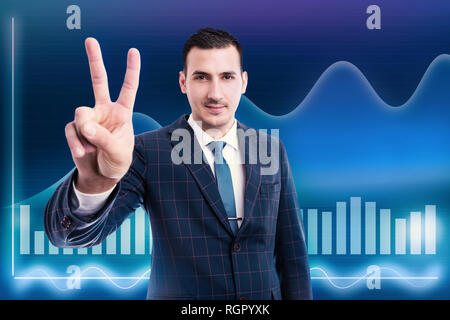 Businessman showing la victoire avec l'index et le majeur comme l'augmentation du marché en stock graphique sur fond bleu Banque D'Images