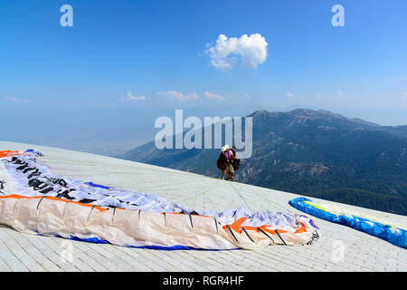 Parapentiste disposés sur le sol, les montagnes et le ciel dans la distance Banque D'Images