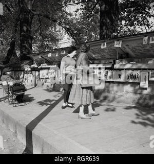 Années 1950, historique, Paris, bouquinistes, deux dames parcourt l'une des attractions célèbres de la ville, le plein-air et des étals de livres anciens que le commerce par la Seine. Banque D'Images