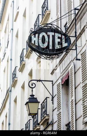 L'usure du panneau en fer forgé d'un modeste hôtel sur la façade d'un ancien bâtiment avec une lumière de rue vintage dans un quartier touristique de Paris. Banque D'Images