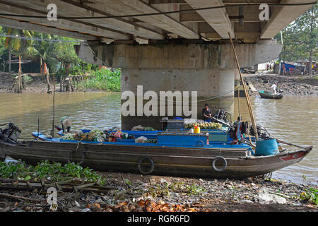Can Tho, Vietnam - 30 décembre 2017. Les vendeurs de fruits sur leurs bateaux à l'ombre d'un pont après avoir passé la matinée, vente de fruits et légumes par Banque D'Images