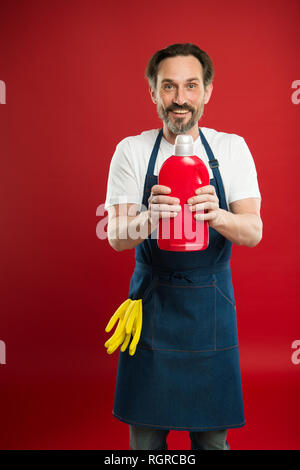 Service de nettoyage et de service à la personne. L'homme à tenir avec des gants tablier bouteille plastique savon liquide de nettoyage chimique. Journée de nettoyage d'aujourd'hui. Accueil nettoyage barbu. La garde de la propreté et l'ordre. Banque D'Images