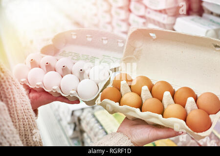 Femme avec des paquets en carton blanc et brun oeufs dans le magasin Banque D'Images