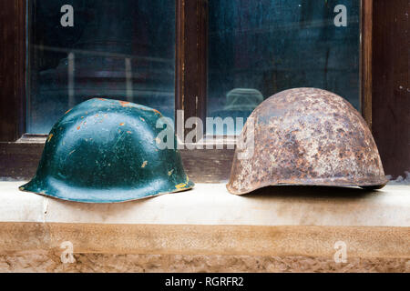 Les casques de soldat affiché devant une fenêtre, Saranda, Albanie Banque D'Images