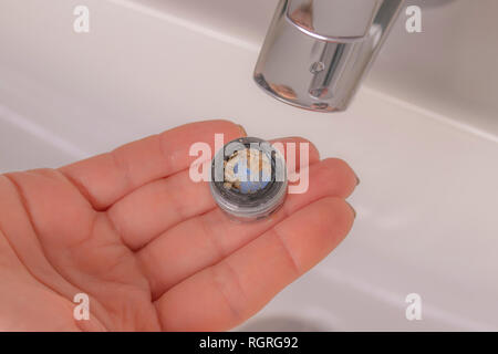 Réparation de la grue aérateur. Purification de l'aérateur de dépôts. La main de la jeune fille tient en mains un vieux calcaire sale de l'aérateur mixe Banque D'Images