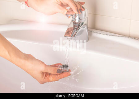 Réparation de la grue aérateur. L'aérateur de nettoyage de dépôts. Main de la jeune fille se lave avec de l'eau sale d'un aérateur de calcaire de la console. Banque D'Images