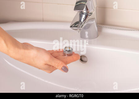 Réparation de la grue aérateur. Purification de l'aérateur de dépôts. La main de la jeune fille tient en mains un vieux calcaire sale de l'aérateur mixe Banque D'Images