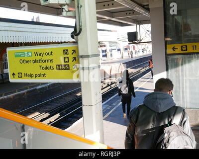 Descendre les escaliers avec les autres usagers sur les plates-formes à à Clapham Junction gare avec des signes visibles. Banque D'Images