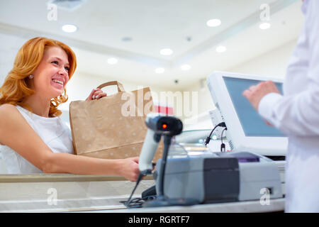 Paiement sans fil en utilisant la technologie NFC et smartphone. Close up. Female customer paying with smart phone en boutique. Close Up shopping Banque D'Images